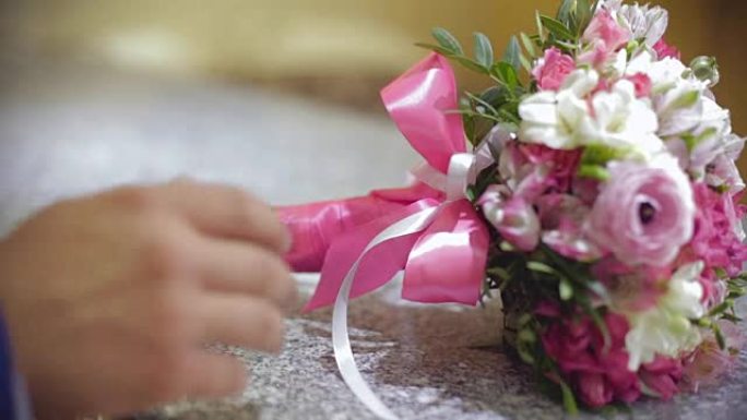 新郎为新娘拿结婚戒指和鲜花。庆祝活动的准备。特写。