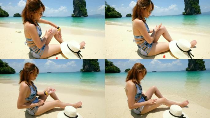 4K 2镜头: 一名妇女坐在沙滩上，在晒日光浴前在皮肤上使用防晒霜。
