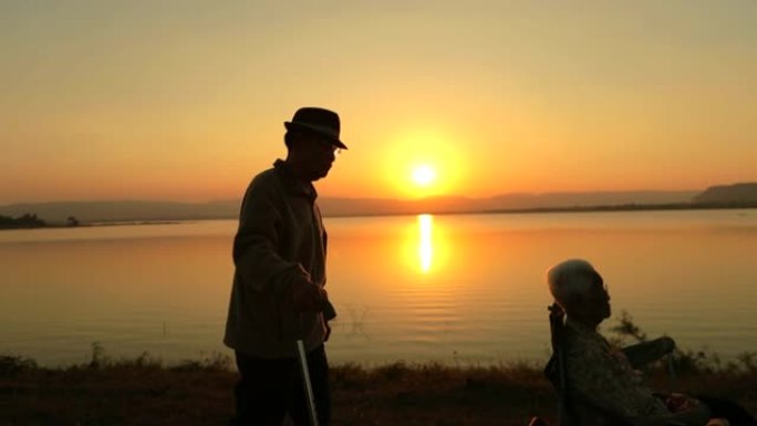 资深亚洲男性与资深亚洲女性一起散步，在湖边欣赏日落美景，慢动作