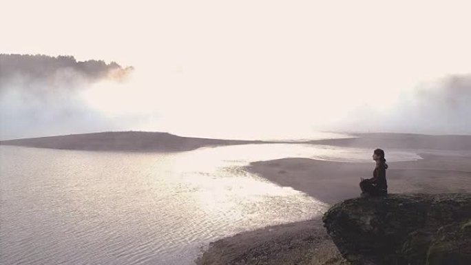 快乐的年轻女子在莲花位置练习瑜伽。无人机镜头