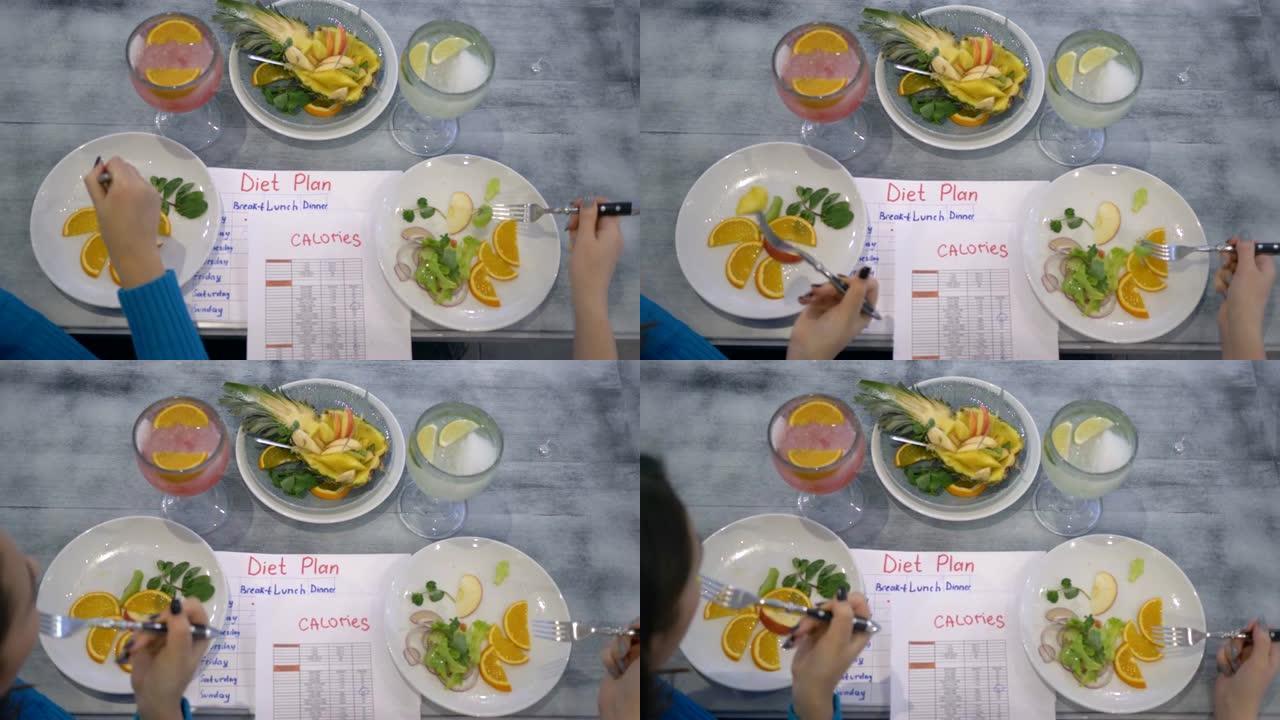 健康的纯素食食品，女孩从坐在桌子上的盘子里吃水果，卡路里表和饮食计划