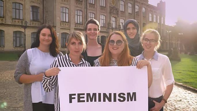 各种年轻的高加索女权主义者站在外面，带着标志和微笑