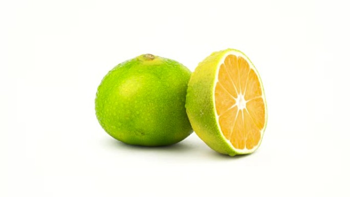 用水滴将绿色橘子果实切成一个整体和一半。在转盘上旋转。孤立在白色背景上。特写。宏观。