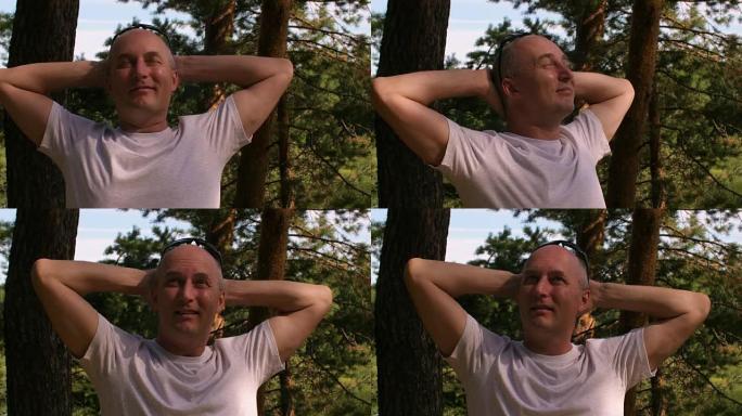 穿着白色t恤的快乐秃头男人在夏季森林或公园放松