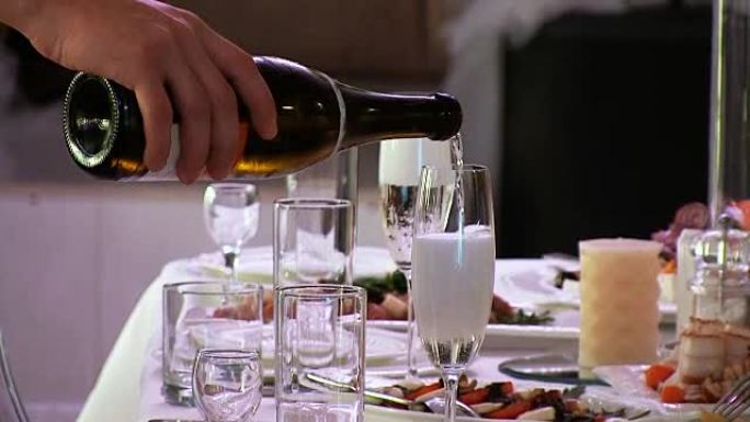 服务员将香槟白起泡酒倒入玻璃杯中。泡沫上升。一家餐馆。