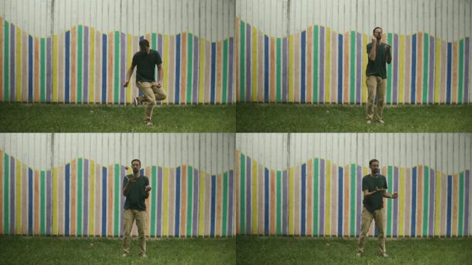 手和腿的男人艺人在背景中展示了用球杂耍，杂耍，慢动作，五颜六色的墙。