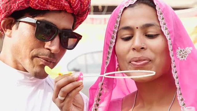迷人的拉贾斯坦夫妇吹泡泡和穿着民族传统印度服装在Pushkar骆驼博览会，印度