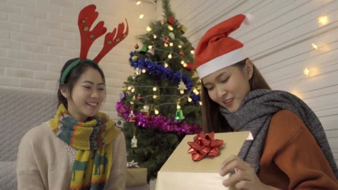 年轻的亚洲妇女在圣诞节和新年快乐时打开礼物盒时感到兴奋。