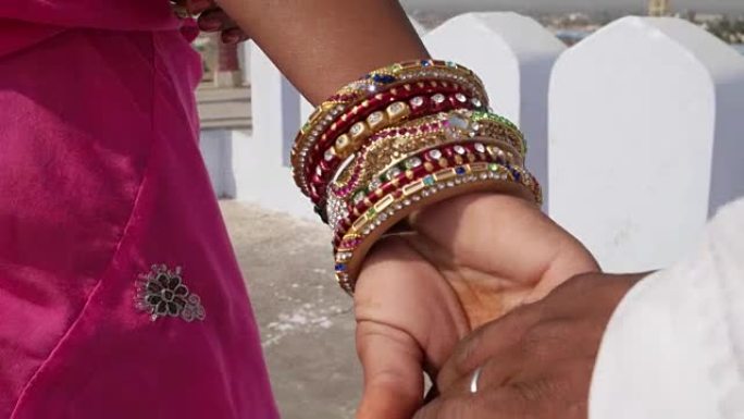 一对夫妇的手与手镯和传统的印度服装的特写