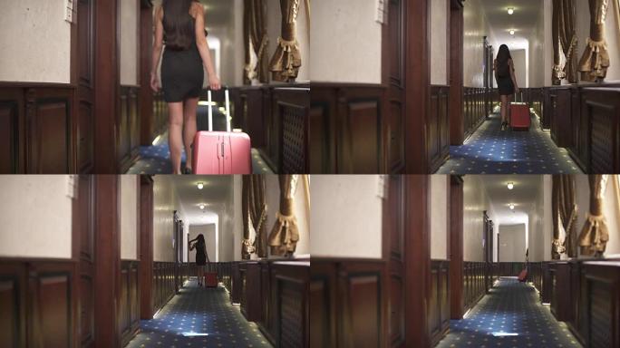 一张空荡荡的酒店走廊的照片。一个黑发女人正拿着一个拉杆箱沿着走廊走。在走廊的尽头，她向右拐，消失了