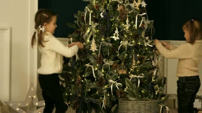 小女孩针织毛衣在灯光下的圣诞树上挂饰