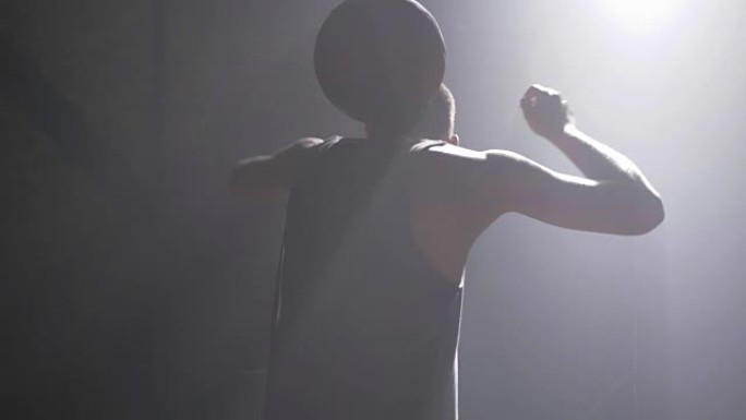 篮球运动员在黑暗的体育馆里用烟雾表演不同的技巧和旋转球