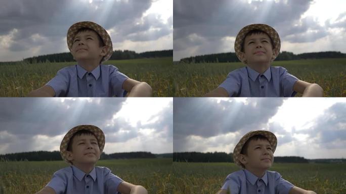 戴帽子的梦想家男孩看着田野里美丽的天空