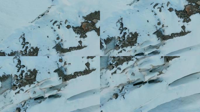 鸟瞰图特写边缘流动的冰川覆盖着高山上的雪和石头。冰川融化的自然破坏和全球变暖