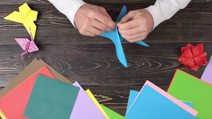 男人用蓝纸折叠折纸。