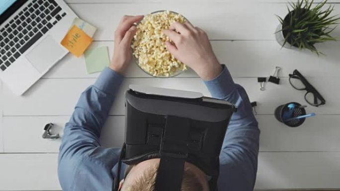 男人使用VR耳机看电影并吃爆米花