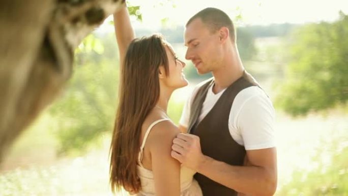 美丽的年轻情侣在浪漫的风景中拥抱。中景镜头。