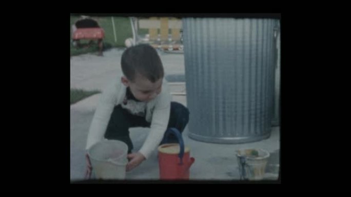 1961可爱的小男孩玩花园软管水和水桶