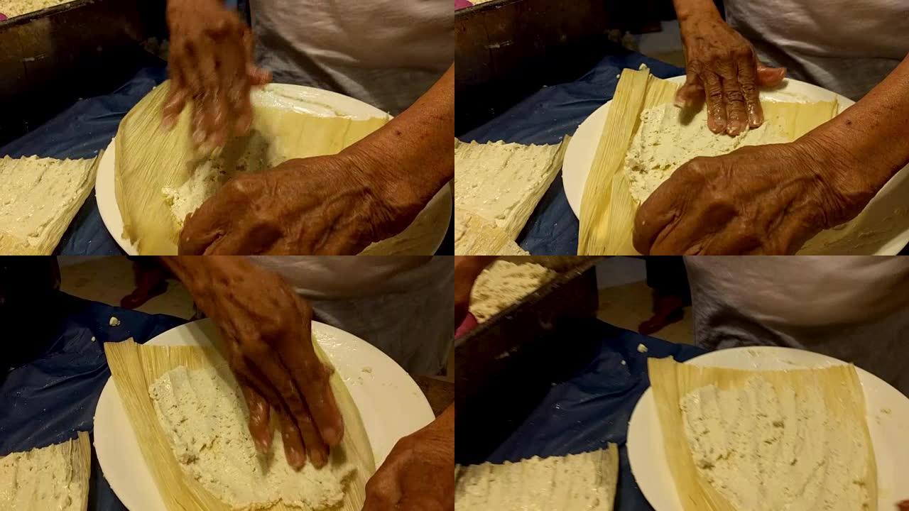 做玉米粉蒸肉。一位墨西哥老年妇女在玉米皮上撒上masa。