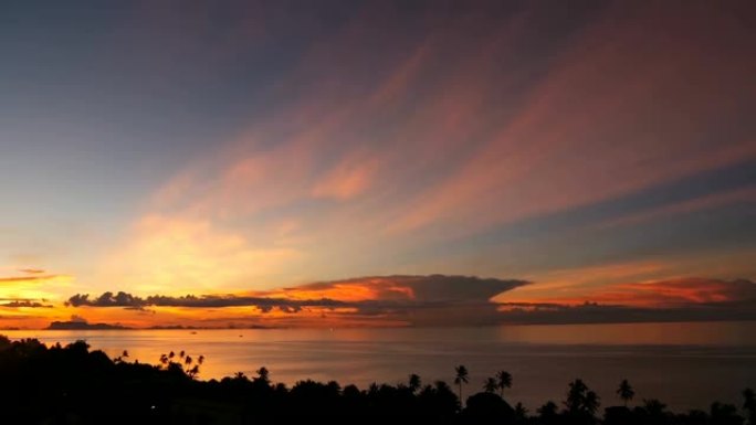雄伟的热带橙色夏季延时日落在海上，山脉轮廓。鸟瞰戏剧性的黄昏，海洋岛屿上金色多云的天空。生动的黄昏海