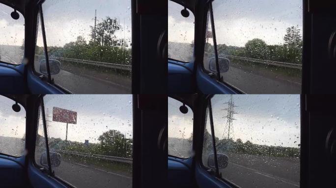 在雨天行驶时，透过旧复古汽车的侧窗观看。在乡下开车时，雨滴落在老式汽车的玻璃上。关闭慢动作