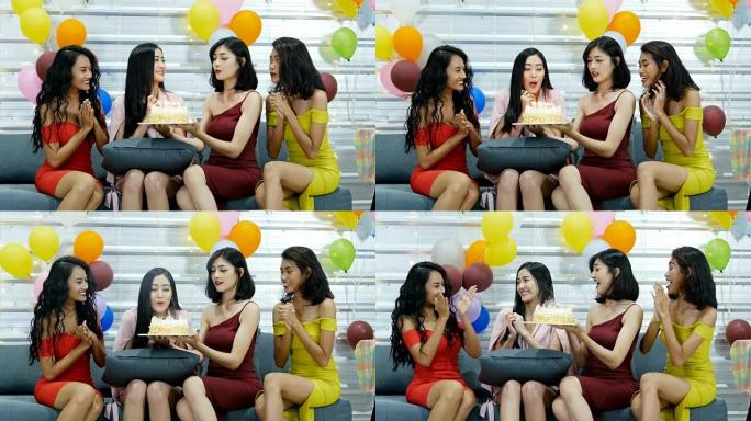 一群朋友为美丽的女人过生日，并在夜间酒吧一起庆祝。快乐微笑的亚洲女孩用她的生日蛋糕吹蜡烛。4k分辨率