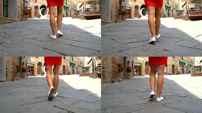 意大利托斯卡纳的苏韦雷托。穿着红色连衣裙的女孩走在城市街道上特写