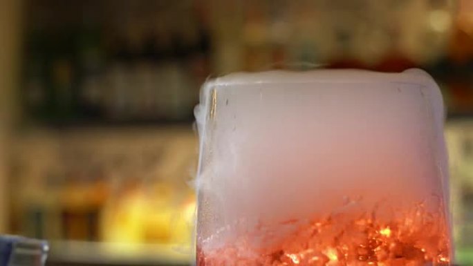 调酒师在酒吧将鸡尾酒与酒杯混合，将酒保手倒入酒杯中