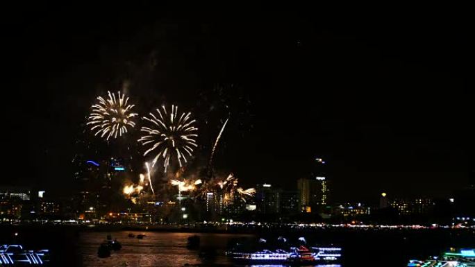 天空中真正的烟花节的4k镜头，用于夜间庆祝，背景为城市景观，海岸一侧前景为海上漂浮的船只