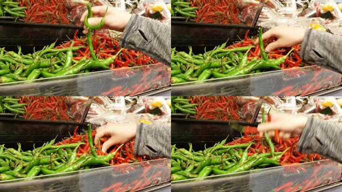 超市内女人的手采摘绿色和红色辣椒的动作