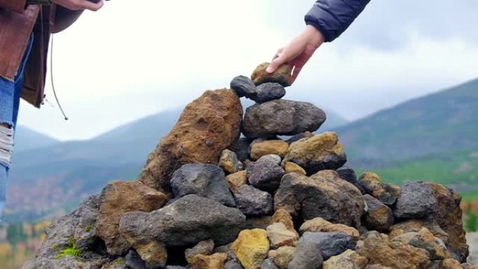信仰和精神概念。两个人试图把一块天然石头扔在堆叠的顶部。山作为背景