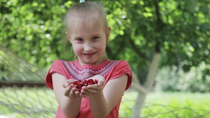 一个甜美的女孩在手掌上拿着草莓。