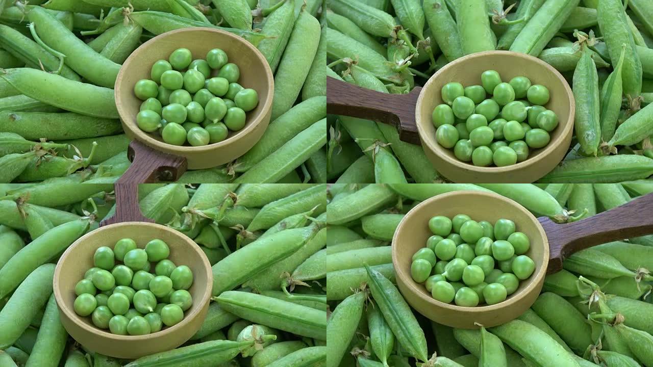 旋转绿色的豌豆荚和勺子中的豌豆