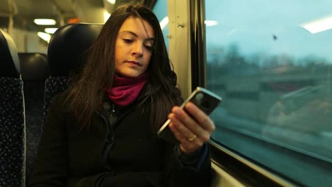 坐火车旅行时拿着手机的女人。4k中拿着智能手机设备的女孩特写