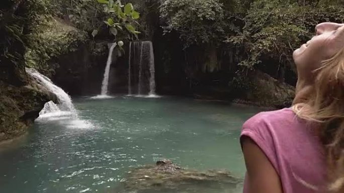 年轻女子正在考虑菲律宾宿雾岛上美丽的瀑布。人们旅行热爱自然的概念。一个人只在和平的环境中享受户外和宁