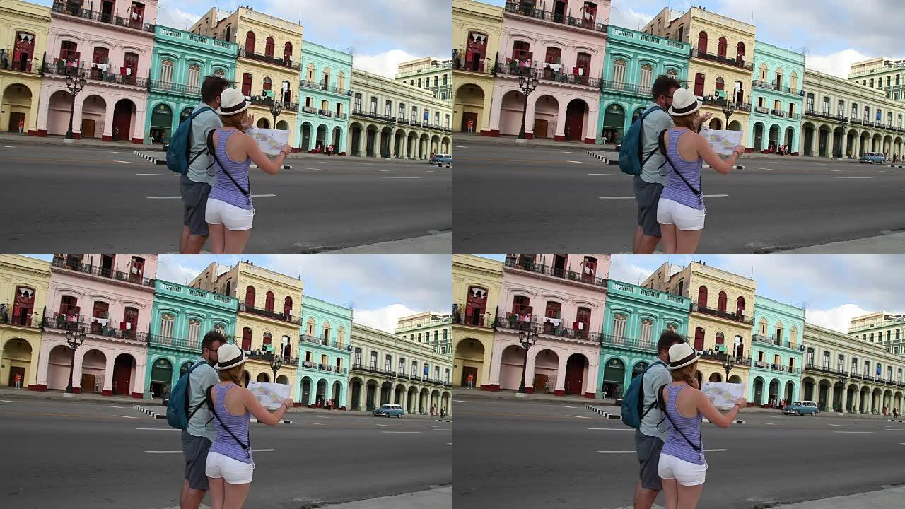 在古巴哈瓦那，有过往的人和汽车的游客在首都主干道附近寻找方向的地图