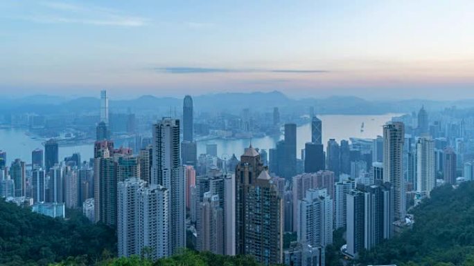 时间流逝从黑夜到白天。香港市区及维多利亚港。智慧城市的金融区。摩天大楼和高层建筑从山顶而来。日出鸟瞰