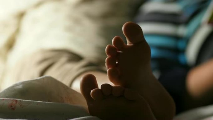 男孩和他的母亲在睡觉前看书的模糊图像聚焦于孩子的腿甜蜜的家庭起重机拍摄