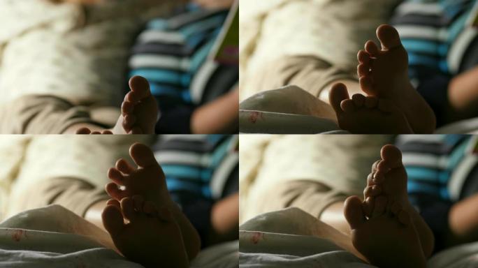男孩和他的母亲在睡觉前看书的模糊图像聚焦于孩子的腿甜蜜的家庭起重机拍摄