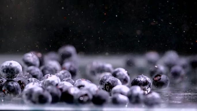蓝莓慢慢落入水中。特写，慢动作。