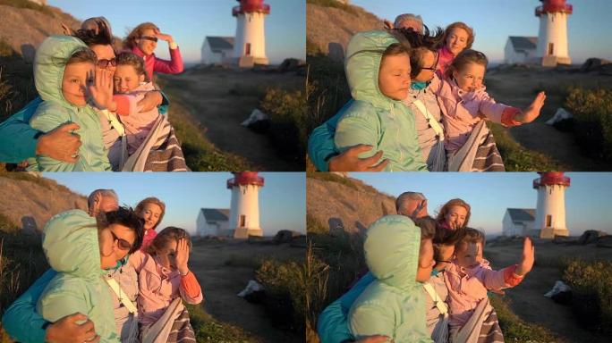 幸福的家庭欣赏着古老的灯塔在岩石的北岸的日落或日出