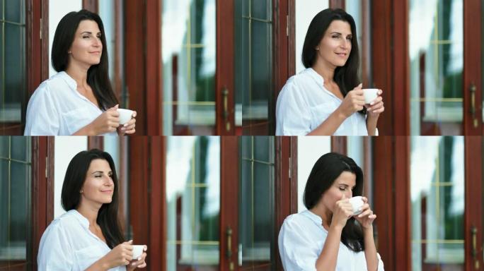 英俊的黑发女人喝着热茶或咖啡，手里拿着白瓷杯
