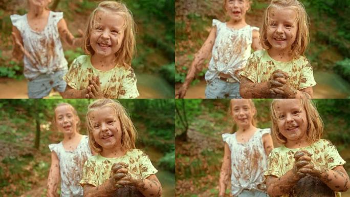 SLO MO小女孩笑着和她的朋友们在森林小溪里玩耍，浑身是泥