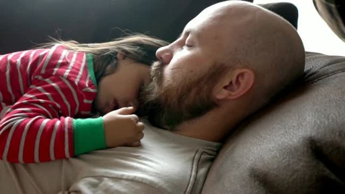 年轻的父亲和女儿在沙发上小睡