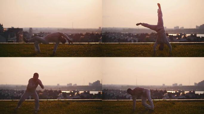 坚强的运动男子在日落时在草地上跳舞卡波耶拉时表现出技巧