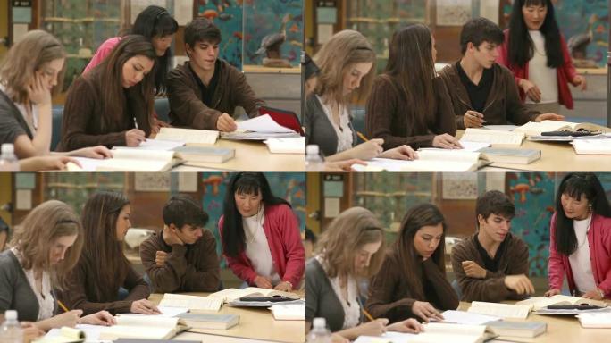 大学生在装满书的桌子上分组学习课程材料