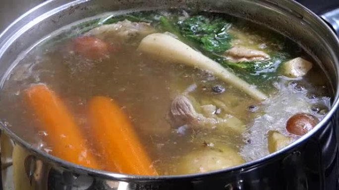 牛肉的特写视图，胡萝卜和洋葱在钢锅中煮沸，用于汤或炖煮。