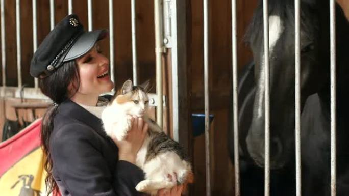 这个迷人的女孩在一匹黑马旁边的马stable里抱着一只猫。