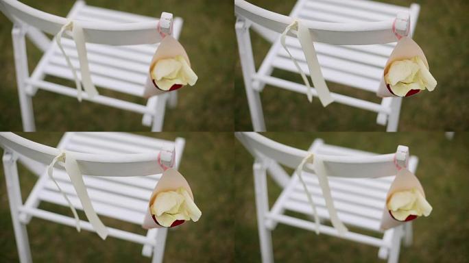 木椅上的婚礼装饰，白色椅子上的丝带和鲜花，婚礼装饰中的小花瓶中的玫瑰花瓣和野花