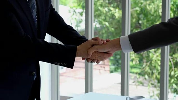 两个亚洲商人合作伙伴在办公室背景，业务概念，盈利协议，合作方面握手
